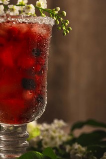 Berry soft drink with ice on a wooden background with flowers