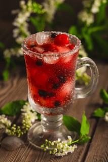 Berry soft drink with ice on a wooden background with flowers