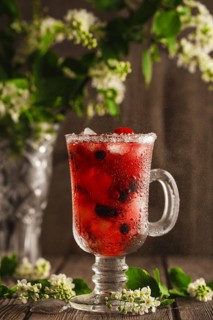 Berry soft drink with ice on a wooden background with flowers