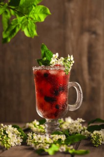 Berry soft drink with ice on a wooden background with flowers