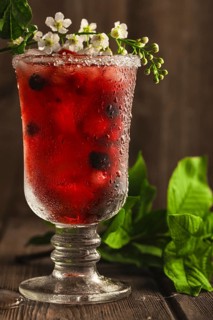 Berry soft drink with ice on a wooden background with flowers