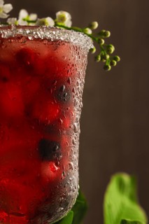 Berry soft drink with ice on a wooden background with flowers