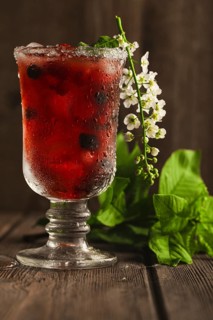 Berry soft drink with ice on a wooden background with flowers