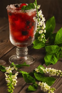 Berry soft drink with ice on a wooden background with flowers