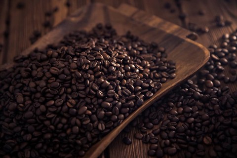 Grains of roasted coffee in the shape of a heart on a white plate