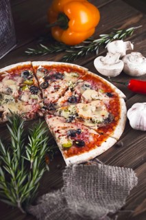 Sliced tasty fresh pizza with mushrooms and sausage on a wooden background. View from above. Close-up