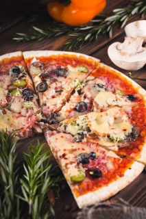 Sliced tasty fresh pizza with mushrooms and sausage on a wooden background. View from above. Close-up