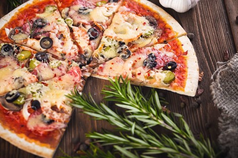 Sliced tasty fresh pizza with mushrooms and sausage on a wooden background. View from above. Close-up