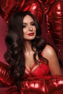 Sexy woman in red lace lingerie and balloons with hearts posing in the studio on Valentine's Day