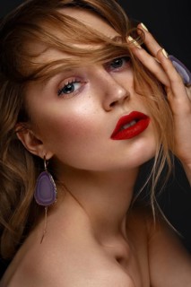 Beautiful girl with red lips and classic makeup and curls with large jewelry. Beauty face. Photo taken in the studio