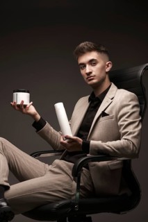 Handsome man hairdresser in a suit with a cosmetic in his hands. Photo taken in the studio