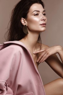 A beautiful girl with classic make-up and a hairstyle in a trendy designer coat posing in a studio. Beauty face