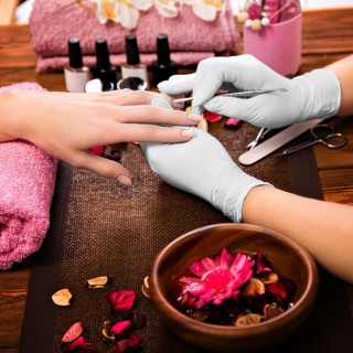 Closeup finger nail care by manicure specialist in beauty salon. Manicurist clear cuticle professional tool for manicure and pedicure