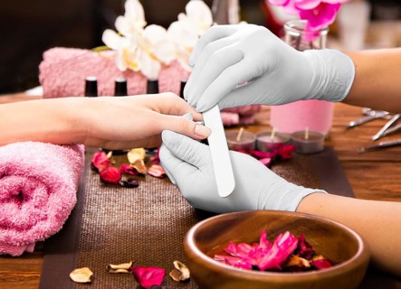 Closeup finger nail care by manicure specialist in beauty salon. Manicurist clear cuticle professional nail file for manicure and pedicure