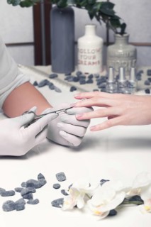 Closeup finger nail care by manicure specialist in beauty salon. Manicurist clear cuticle professional scissors for manicure and pedicure