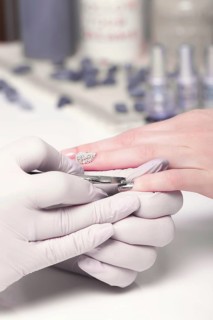 Closeup finger nail care by manicure specialist in beauty salon. Manicurist paints nails with nail polish