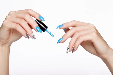 Beautiful summer blue manicure on female hand with nail polish. Close-up. Picture taken in the studio