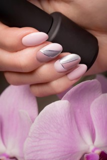 Purple neat manicure on female hands on a background of flowers. Nail design