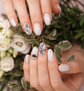 Gentle neat manicure on female hands on a background of flowers. Nail design