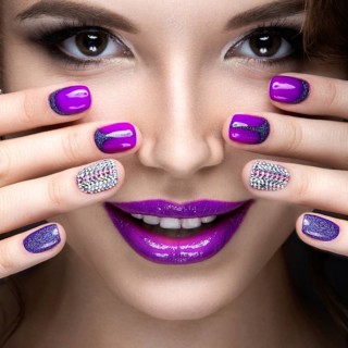 Beautiful girl with a bright evening make-up and purple manicure with rhinestones. Nail design. Beauty face. Picture taken in the studio on a black background