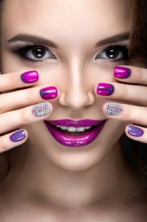 Beautiful girl with a bright evening make-up and purple manicure with rhinestones. Nail design. Beauty face. Picture taken in the studio on a black background