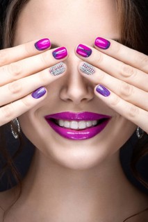 Beautiful girl with a bright evening make-up and purple manicure with rhinestones. Nail design. Beauty face. Picture taken in the studio on a black background