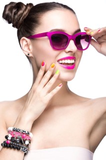 Beautiful girl in pink sunglasses with bright makeup and colorful nails. Beauty face. Picture taken in the studio on a white background