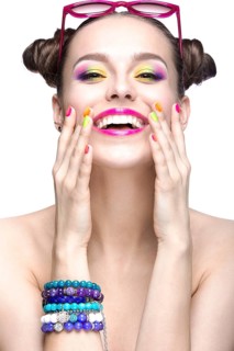 Beautiful girl in pink sunglasses with bright makeup and colorful nails. Beauty face. Picture taken in the studio on a white background