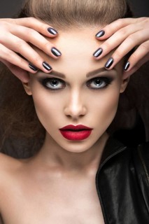 Beautiful girl in leather jacket with bright makeup and manicure Cat's Eye. Beauty face. Nail Design. Picture taken in the studio on a black background