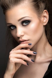 Beautiful girl in leather jacket with bright makeup and manicure Cat's Eye. Beauty face. Nail Design. Picture taken in the studio on a black background