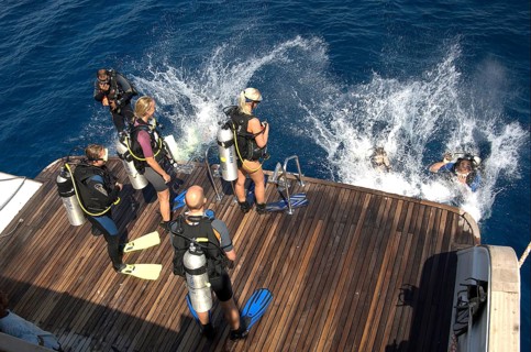 Divers Sport divers jump from dive deck of dive ship for dive cruise into sea water