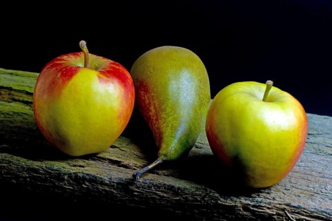 Two apples and a pear on an old wooden beam