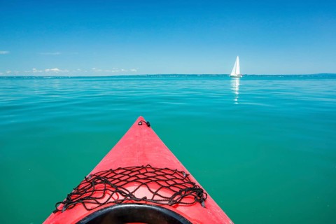 Bow of red kayak with view over the expanse and turquoise waters of Lake Constance