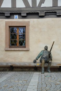 Sculpture Man sitting with rifle in front of half-timbered house Weapons Museum and window
