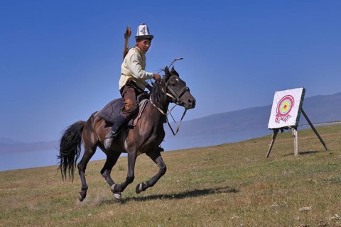 Kyrgyz nomad shooting arrows on a target while galloping
