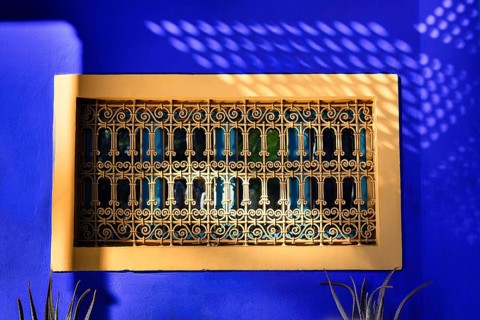 Ornate window grille in a blue wall