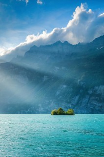 Evening sunshine on Lake Walen with chive island in the turquoise water and mountain range Schaeren in the background