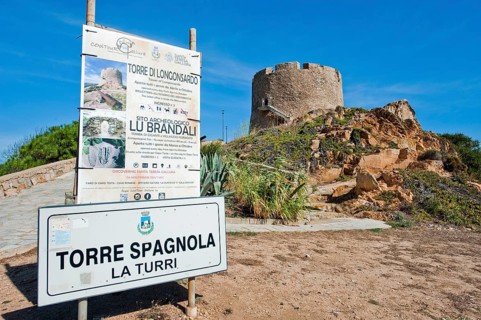 Left tourist information sign Sign for in the background historical Spanish fortified defence tower Torre Spagnola La Turri