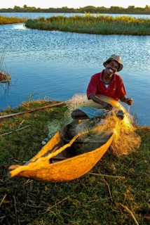 Fisherman repairs his net at sunset