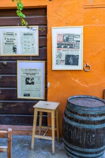 Street cafe with framed historical newspapers in Via Cardenti