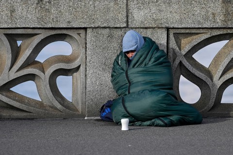 Homeless person with sleeping bag and cup