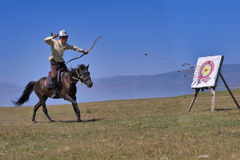 Kyrgyz nomad shooting arrows on a target while galloping