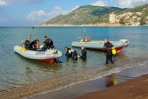 Divers on the beach getting into diving boats inflatables