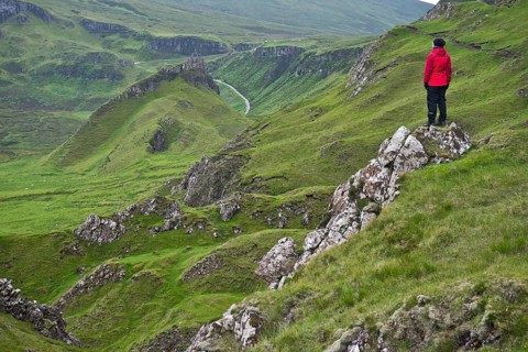 Hiker in red outdoor jacket in the bizarre rock world of Quiraing