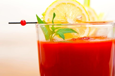 Fresh tomato juice gazpacho soup on a glass over white wood table