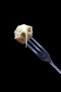 Bread cubes with melted cheese on fondue fork