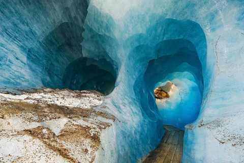 Visitors Wooden footbridge through ice tunnel in the Rhone glacier