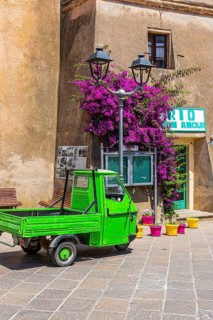 Green Piaggio Ape utility vehicle in front of the cathedral of Rio nell Elba