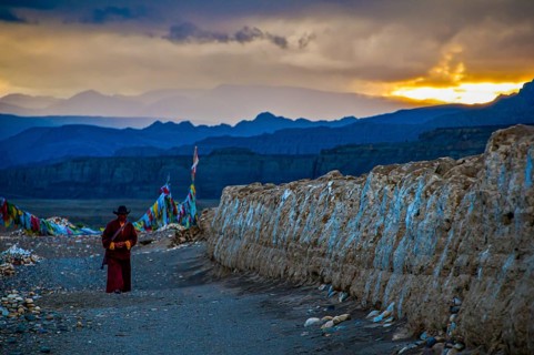 Monk walks along an eroded mud wall in the kingdom of Guge