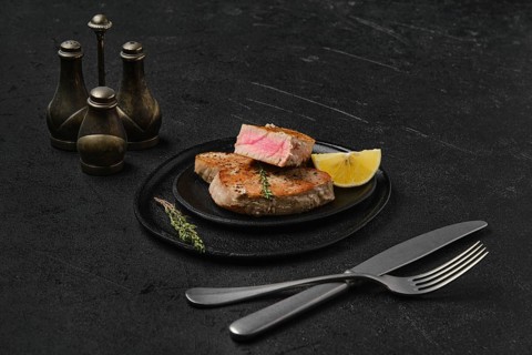 Fried tuna steak on black background